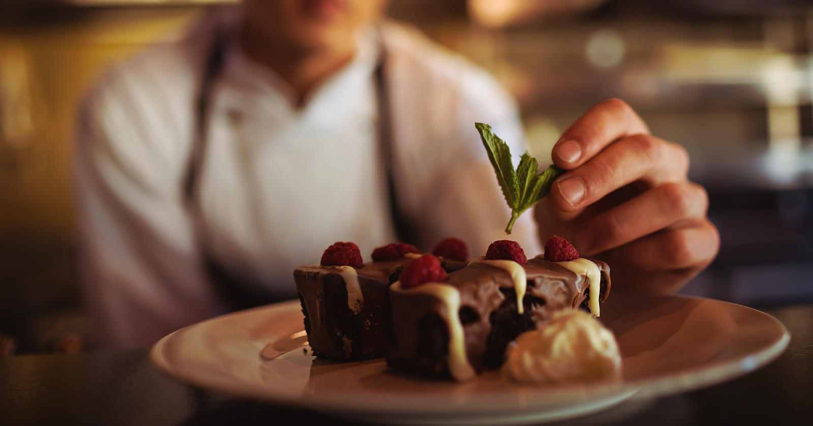 Close-up of male chef garnishing dessert plate in commercial kitchen